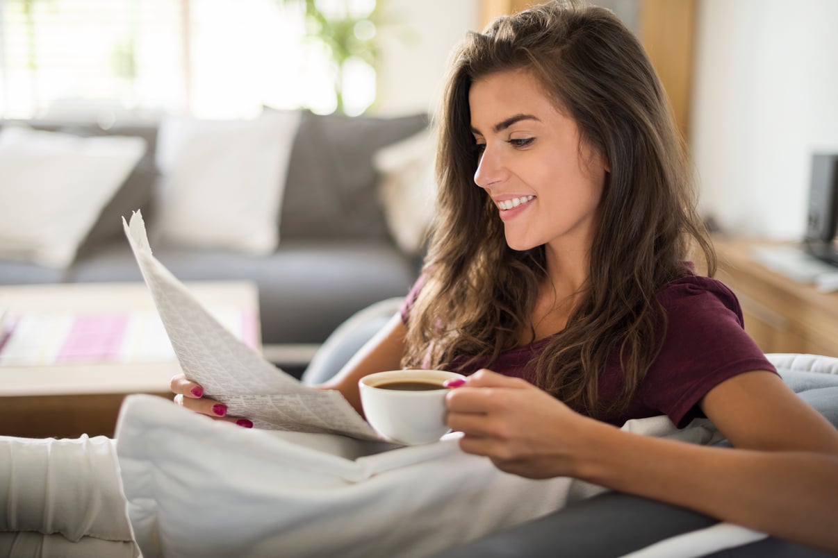 mujer-joven-leyendo-periodico-tomando-cafe