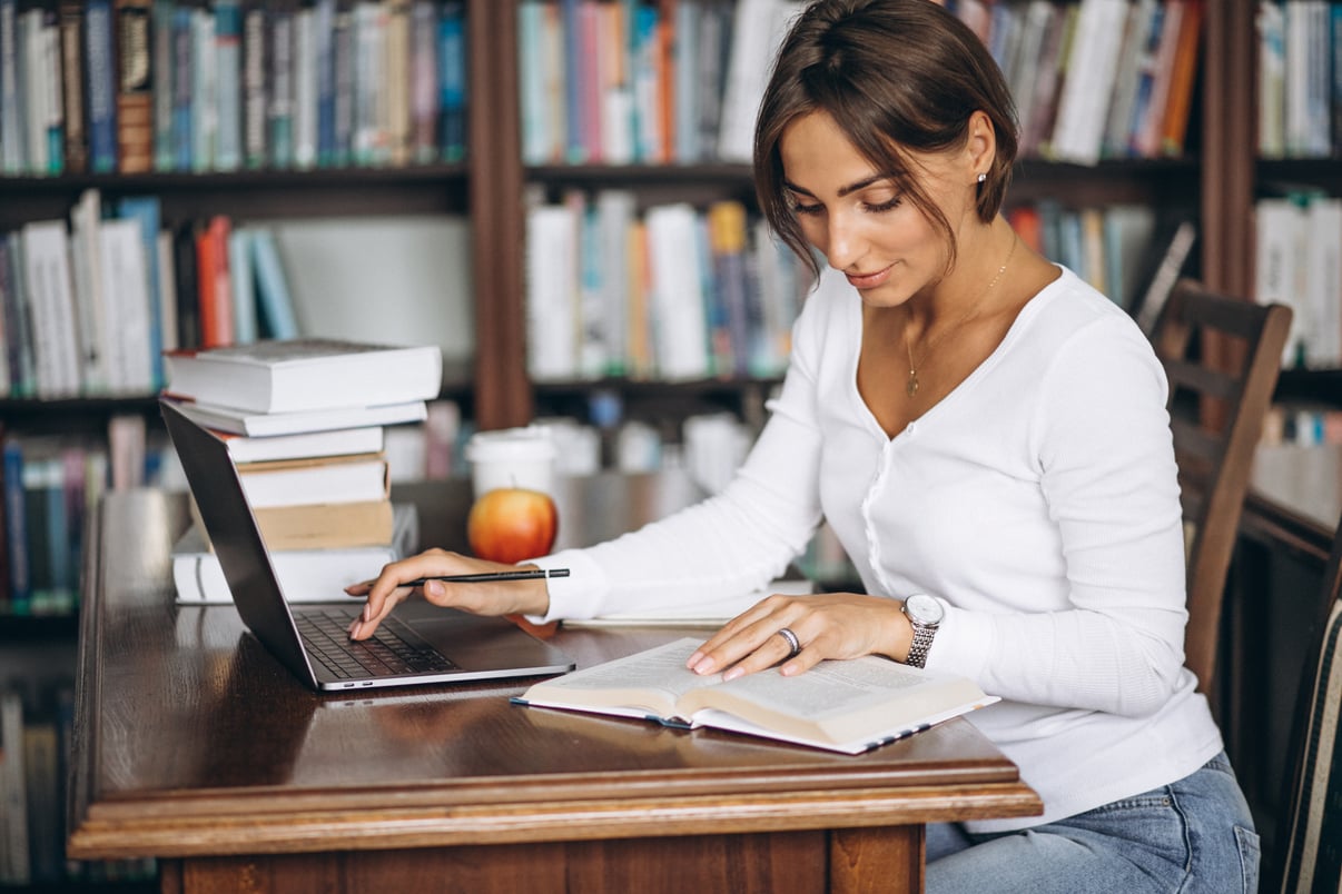 mujer-joven-sentada-biblioteca-libros-computadora