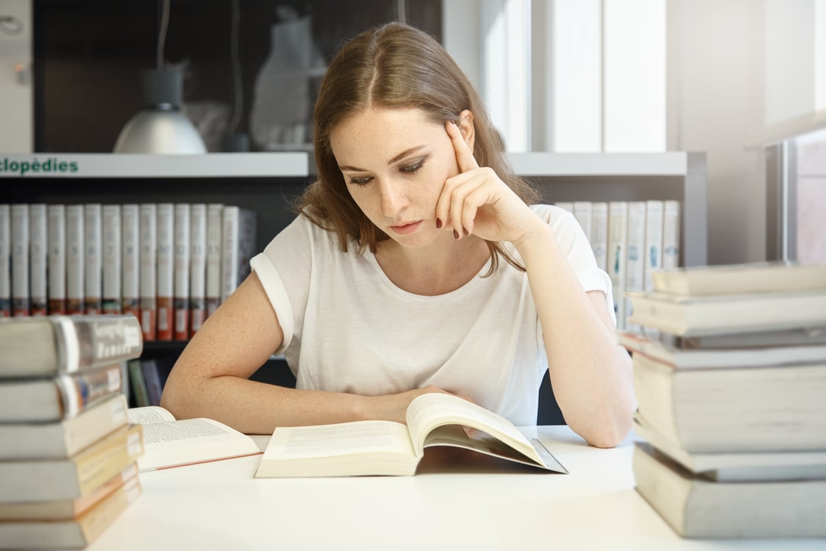 mujer-joven-sentada-biblioteca-portatil