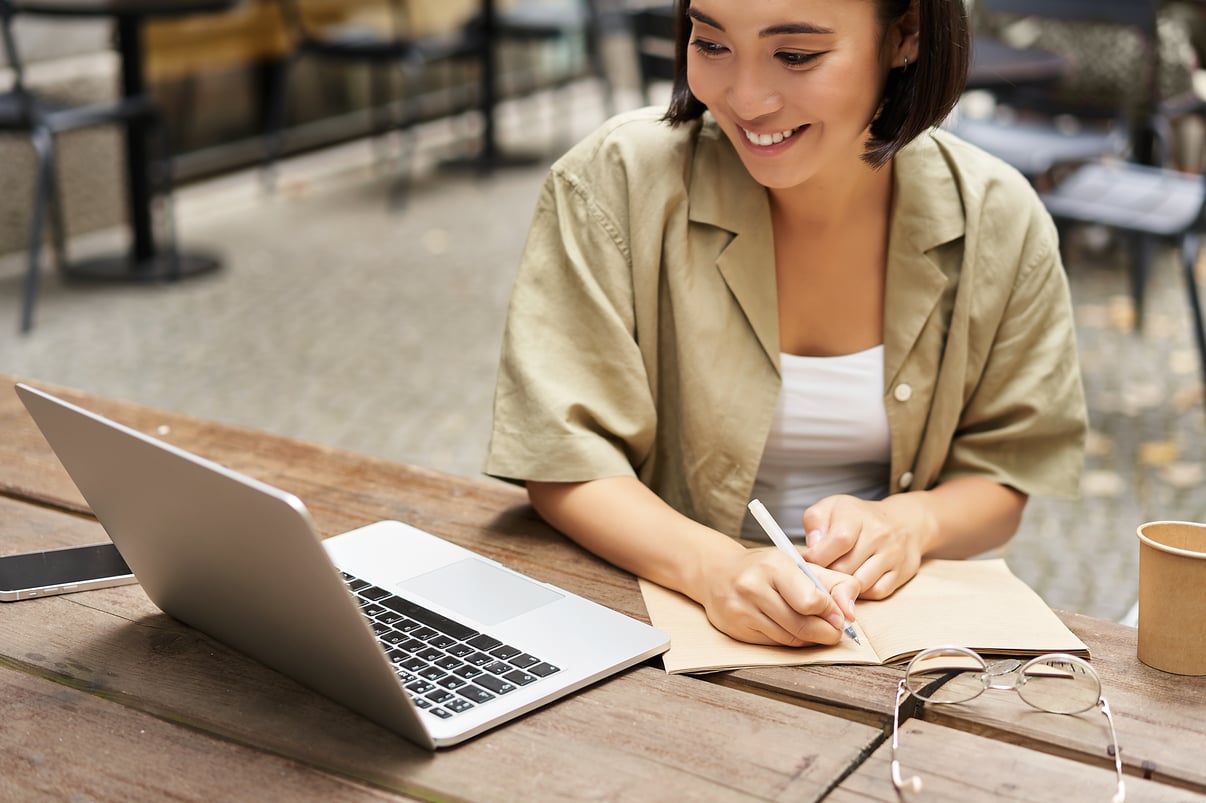 retrato-joven-que-estudia-linea-sentada-laptop-escribiendo-notas-mirando